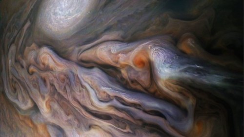 A swirling, colorful depiction of Jupiter's atmosphere, showcasing clouds and storms in shades of orange, brown, and blue.