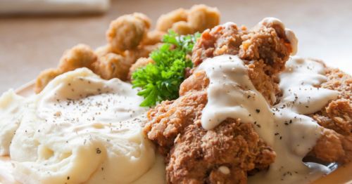 Closeup of a plate of fried chicken next to a pile of mashed potatoes and fried okra