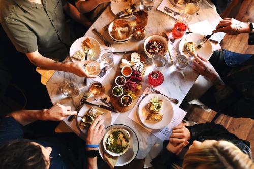 A top-down view of a dining table with various dishes, drinks, and people enjoying a meal together.