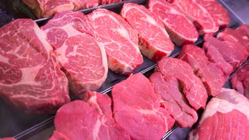 A display of various cuts of raw beef, showcasing marbled and lean sections in a butcher shop.