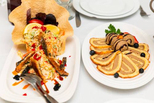 A colorful dish with salad in a tortilla bowl and a sliced dessert roll with chocolate and fruit garnishes.
