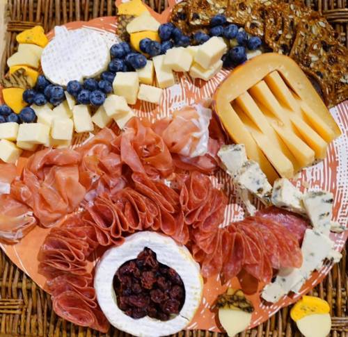 A colorful charcuterie board featuring various cheeses, meats, fruits, and crackers arranged artfully.