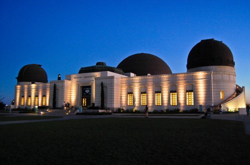 The Griffith Observatory illuminated at dusk, showcasing its iconic domes and architectural details against a twilight sky.