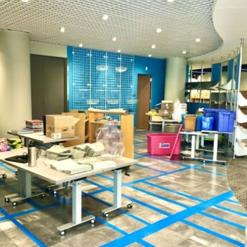 A spacious room with blue walls, tables, boxes, and storage bins, indicating an organized workspace or storage area.