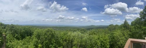 Panoramic view of lush green hills under a blue sky with fluffy clouds.