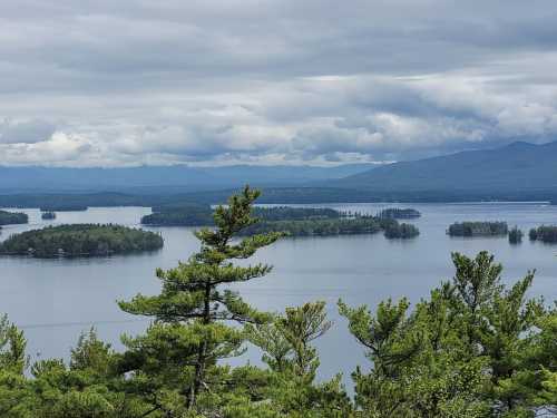 A serene view of a lake surrounded by islands and lush greenery under a cloudy sky.