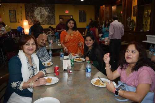 A group of four people enjoying a meal at a festive gathering, with food and drinks on the table.