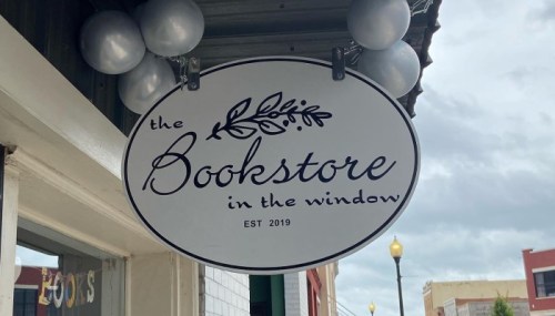 Sign for "the Bookstore in the Window," established 2019, with decorative balloons above it.