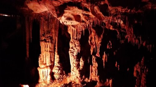 Stalactites and stalagmites in a dimly lit cave, showcasing natural rock formations and textures.