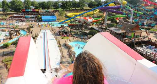 A view from the top of a water slide, overlooking a vibrant water park with slides and pools below.