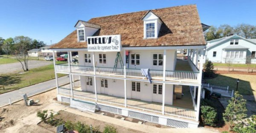 A two-story building with a sign reading "Field's Seafood & Oyster Bar," featuring a porch and surrounding landscaping.