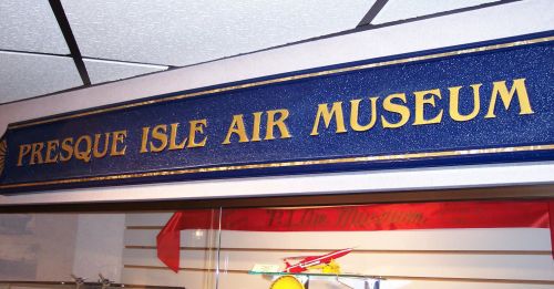 Sign for Presque Isle Air Museum, featuring bold gold lettering on a blue background.