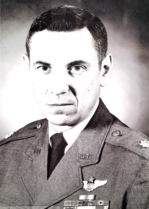 Black and white portrait of a serious man in a military uniform with medals, looking directly at the camera.