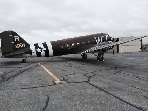 A vintage military aircraft parked on a tarmac, featuring a dark camouflage pattern and star insignia.