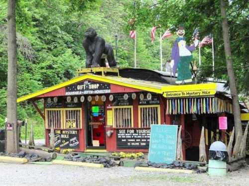 A quirky gift shop with a gorilla statue on the roof, surrounded by trees and colorful decorations.