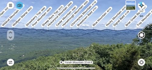 A panoramic view of mountains labeled with their names and elevations against a clear blue sky.