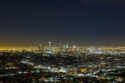 A panoramic view of a city skyline at night, illuminated by countless lights against a dark sky.