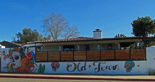 Colorful mural on a building in Old Town, featuring a skull, flowers, and vibrant designs against a clear blue sky.