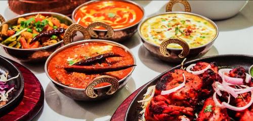 A vibrant spread of Indian dishes in decorative bowls, featuring curries, grilled chicken, and garnishes.