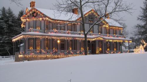 A beautifully decorated house covered in snow, adorned with colorful holiday lights and wreaths.