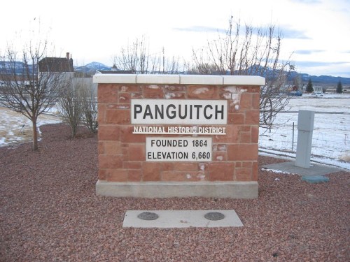 Sign for Panguitch National Historic District, founded in 1864, with an elevation of 6,660 feet. Snowy landscape in background.