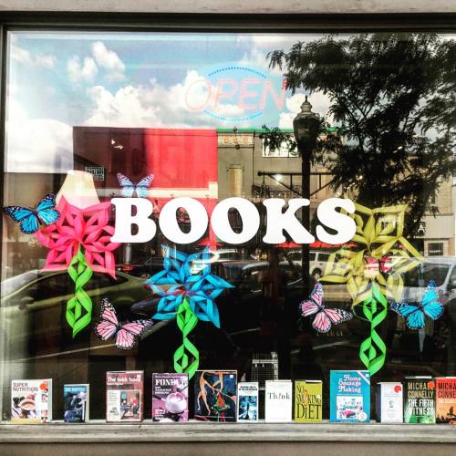 Colorful window display of a bookstore featuring flowers and butterflies, with the word "BOOKS" prominently displayed.