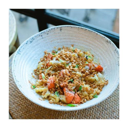 A bowl of savory dish topped with crushed peanuts, green onions, and mixed vegetables.