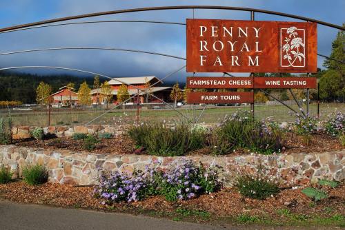 Sign for Penny Royal Farm featuring farmstead cheese, wine tasting, and farm tours, surrounded by flowers and greenery.