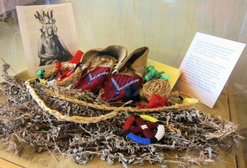 Display of traditional items, including woven crafts, herbs, and a portrait, showcasing cultural heritage.