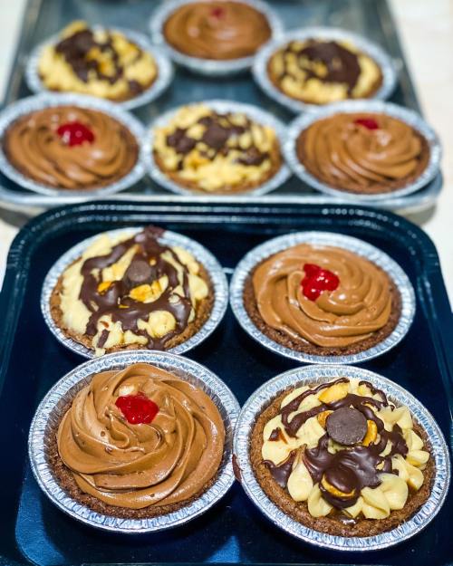 A tray of mini desserts featuring chocolate and peanut butter toppings, some with cherries on top.