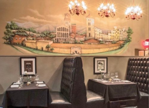 Cozy restaurant interior with elegant booths and a mural of a scenic landscape on the wall.