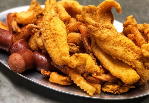 A platter of golden fried fish fillets and sausage links, served on a silver tray.