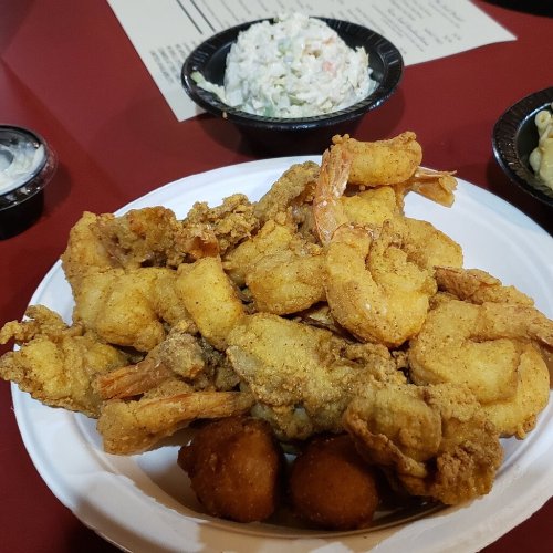 A plate of golden fried shrimp with hushpuppies and a side of coleslaw.