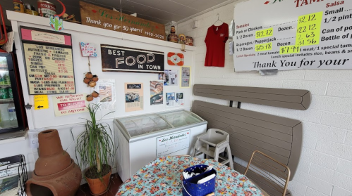 Cozy restaurant interior with a menu board, seating, and a freezer, showcasing a welcoming atmosphere for diners.