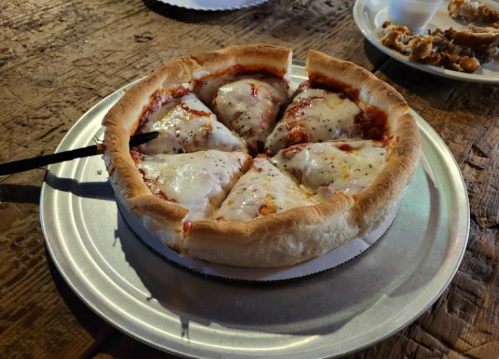 A freshly baked pizza with melted cheese and a thick crust, served on a silver plate.