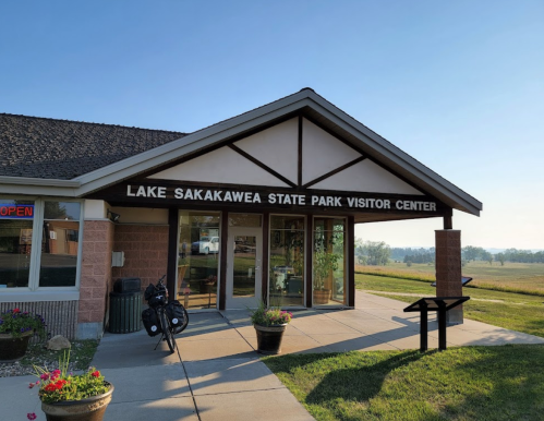Entrance of Lake Sakakawea State Park Visitor Center with a clear sky and green landscape in the background.