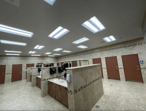 A spacious restroom with multiple stalls, sinks, and bright overhead lighting.