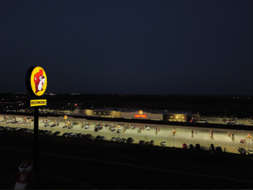 Buc-ee's gas station and convenience store illuminated at night, with a large sign and a parking lot filled with cars.
