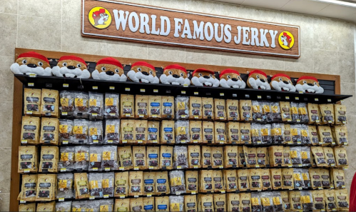 A display of various jerky bags under a sign reading "World Famous Jerky," with plush toys on top.