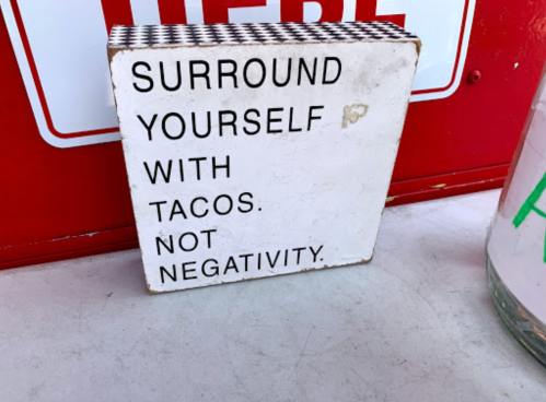 A sign that reads, "Surround yourself with tacos. Not negativity." on a checkered background.
