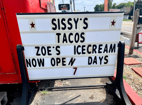 Sign for Sissy's Tacos and Zoe's Ice Cream, announcing they are now open 7 days a week.
