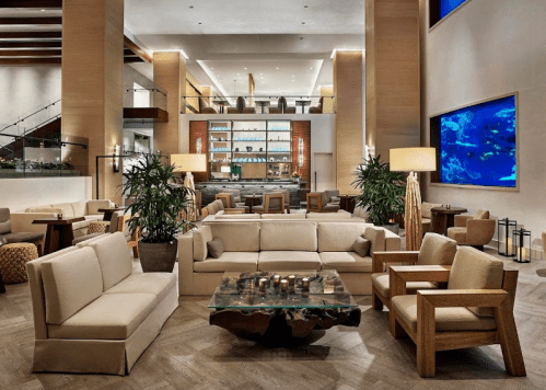 Modern hotel lobby featuring stylish seating, a glass coffee table, and a large aquarium in a bright, open space.