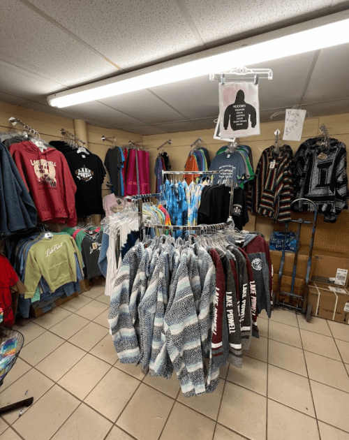 A clothing store display featuring various colorful shirts, hoodies, and sweaters on racks and hangers.