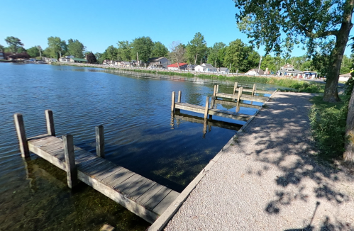 A serene lakeside view featuring wooden docks and a gravel path under a clear blue sky.