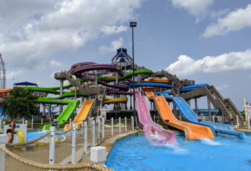A colorful water slide complex with multiple twisting slides and a pool area under a partly cloudy sky.