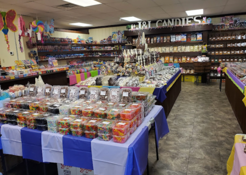 A colorful candy store filled with various sweets, jars, and treats displayed on tables and shelves.