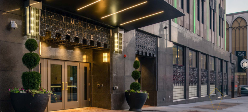 Entrance of the Tulsa Club featuring modern architecture, planters, and illuminated signage.