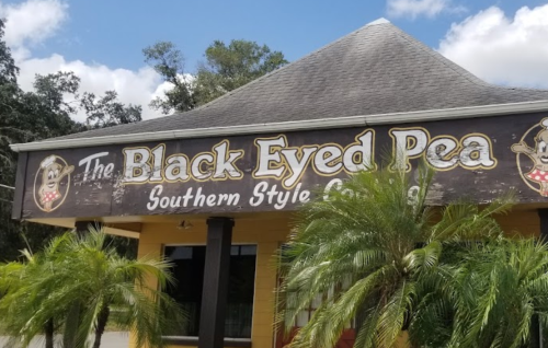 Sign for "The Black Eyed Pea" restaurant featuring Southern-style cuisine, surrounded by palm trees.
