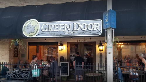A restaurant called "Green Door on 8th" with outdoor seating and a welcoming entrance.