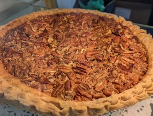 A freshly baked pecan pie with a golden crust and a rich, nutty filling topped with whole pecans.